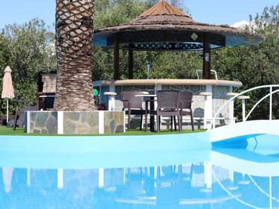 Leisure area with pool bar and chairs set against green trees on a sunny day.