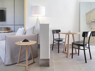 Jasny salon z białą sofą, małym drewnianym stolikiem i częścią jadalną z dwoma krzesłami.