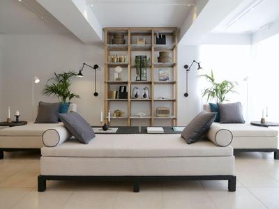 Modern living room with white sofa, gray cushions, and a wall with shelves and plants.