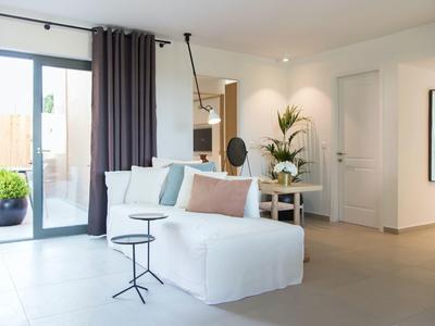 Nowoczesny salon z białą sofą, małymi stolikami i wyjściem na taras.