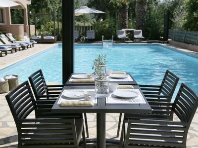 A set dining table next to an outdoor pool with lounge chairs and umbrellas.