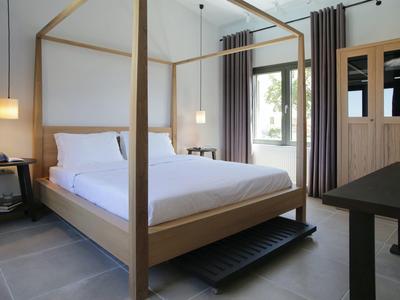 Sypialnia z drewnianym łóżkiem z baldachimem, białą pościelą, stolikiem nocnym i dużym lustrem.