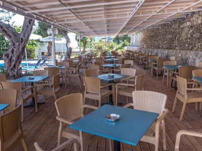 Espace extérieur couvert d'un restaurant avec tables et chaises à côté d'une piscine.