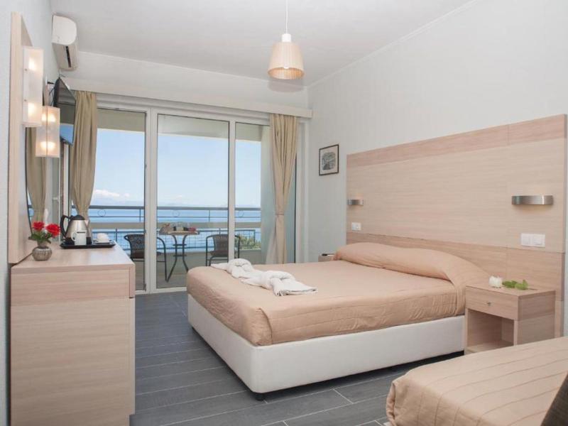 Helles Schlafzimmer mit Doppelbett, Balkon und Meerblick, in sanften Beige- und Holztönen gestaltet.