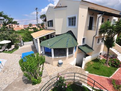 Buitengebied van een hotel met zwembad, tuin en zitplaatsen bij zonnig weer.