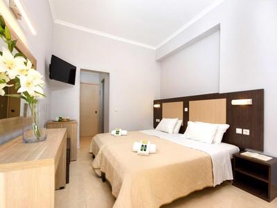 Modernes Hotelzimmer mit zwei Betten, Schreibtisch, Fernseher und Blumendekoration.