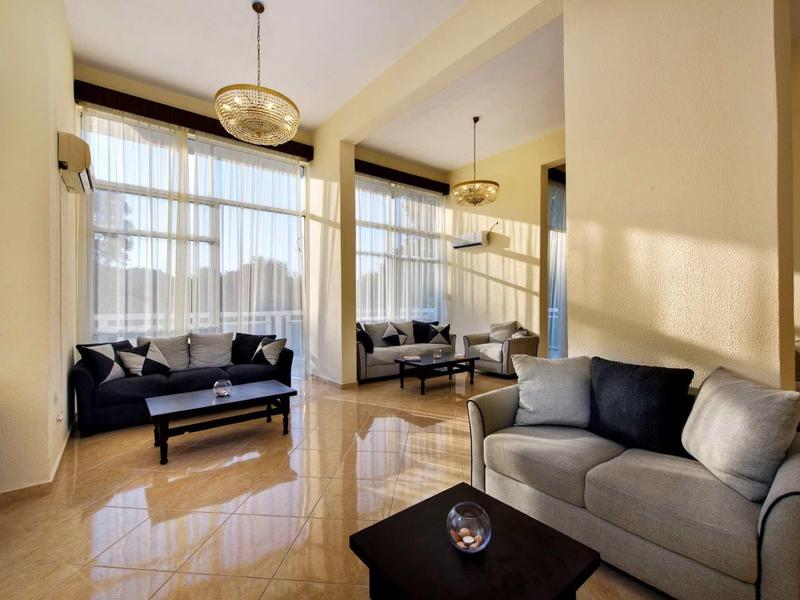 Lichte hotel lounge met grote ramen, moderne banken en planten.