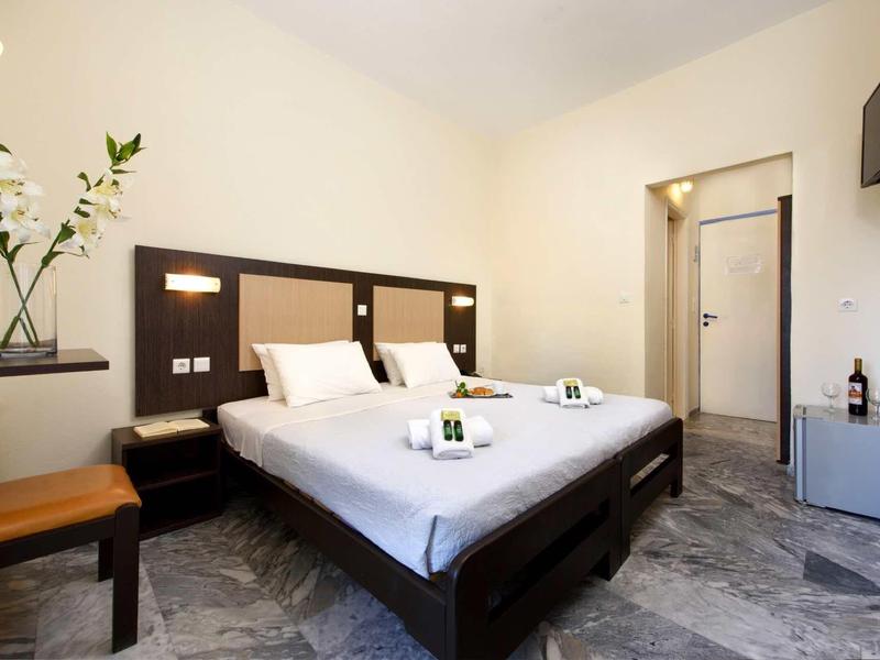 Modern hotelkamer met tweepersoonsbed, flatscreen-tv, stoel en marmeren vloer