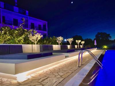 Area piscina illuminata con posti a sedere e piante di notte in un hotel.