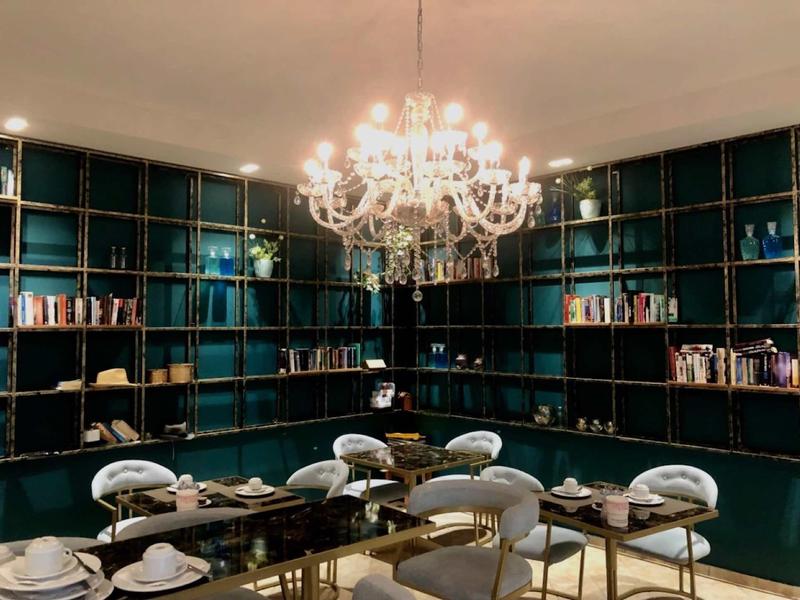 Eleganter Essbereich mit grünem Bücherregal, runden Stühlen und prunkvollem Kronleuchter.