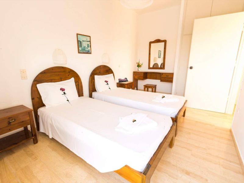 Hell eingerichtetes Schlafzimmer mit zwei Einzelbetten, Holzrahmen und weißer Bettwäsche.