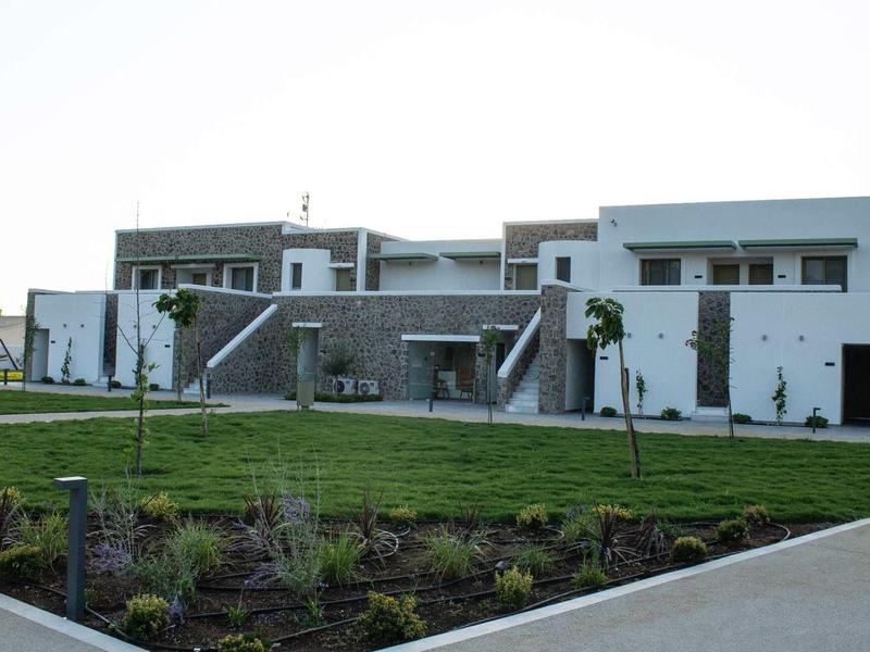 Modernes zweistöckiges Gebäude mit klaren Linien, großen Fenstern und umliegendem Grasfeld.