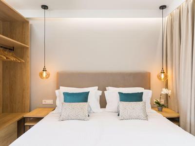 Modernes Schlafzimmer mit großem Bett, grauem Kopfteil, Holz-Nachttischen und hängenden Lampen.