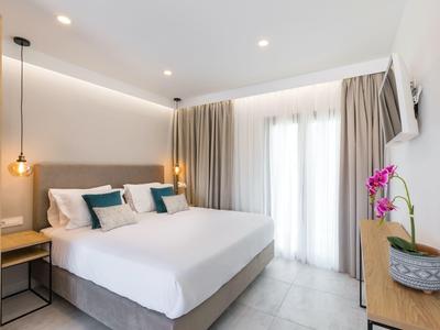 Modernes Schlafzimmer mit großem Bett, grauem Kopfteil, Holz- und weißen Wänden, Vorhängen und Orchidee.