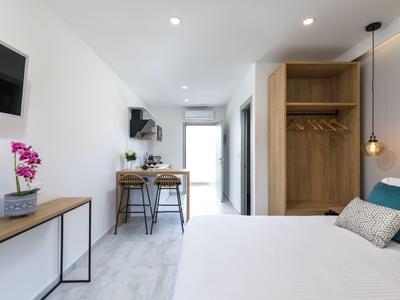 Klares Schlafzimmer mit weißem Bett, hölzernem Kleiderschrank, Schreibtisch und Stühlen, modernes Design.