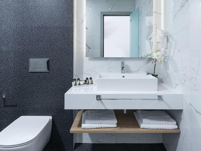 Modernes Badezimmer mit weißer Keramik-Waschtischplatte, rechteckigem Spiegel und grauer Wand.