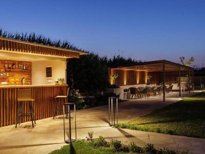 Outdoor bar and seating area at dusk with lighting and clear sky.