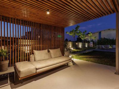 Modern living room with wooden ceiling and cozy sofa next to garden at dusk.