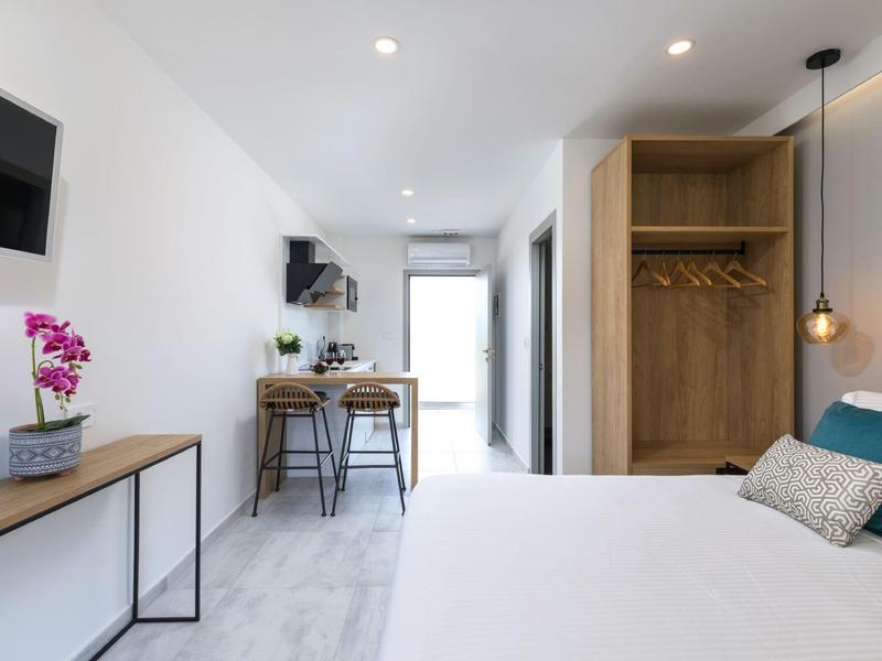 Klares Schlafzimmer mit weißem Bett, hölzernem Kleiderschrank, Schreibtisch und Stühlen, modernes Design.