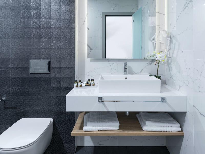 Modernes Badezimmer mit weißer Keramik-Waschtischplatte, rechteckigem Spiegel und grauer Wand.