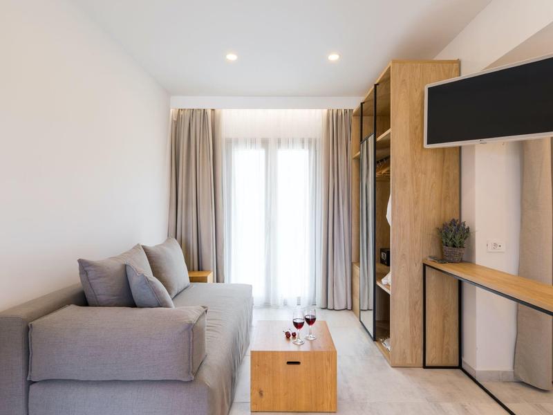 Modernes Wohnzimmer mit grauem Sofa, Holzmöbeln, Flachbildfernseher und großen Fensterfronten.