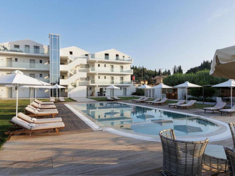 Moderner Hotelpool mit Liegestühlen, Sonnenschirmen und weißem Gebäude im Hintergrund bei klarem Himmel.