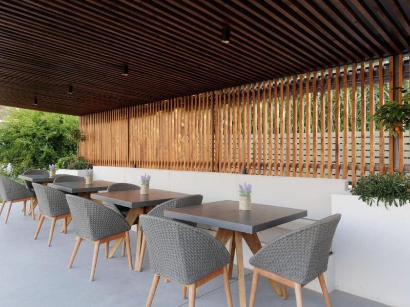 Moderner Außenbereich mit grauen Stühlen, Holztischen und Holzlamellen an der Wand, mit Pflanzen dekoriert.