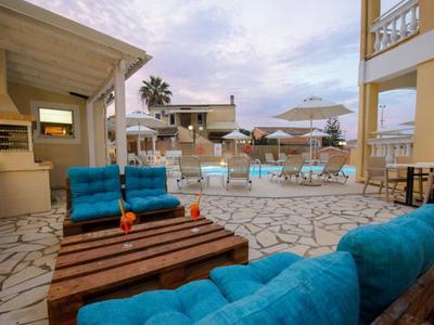 Pohodlná venkovní část s modrými pohovkami a bazénem v pozadí pod modrou oblohou.