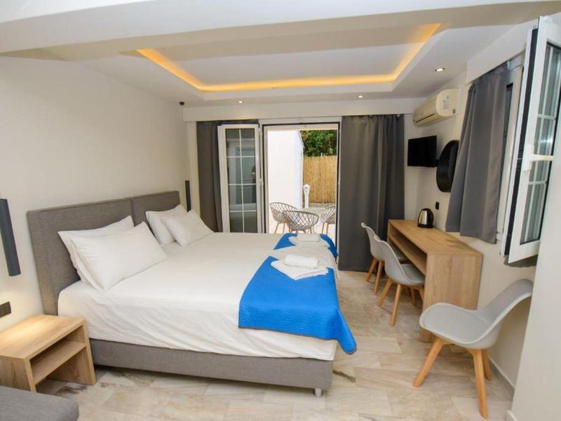 Chambre d'hôtel moderne avec grand lit, bureau, chaise et balcon avec lumière naturelle.