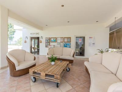 Zona lounge luminosa e accogliente con divani bianchi e un tavolino in legno su ruote.