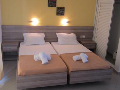 Due letti singoli in una camera d'hotel con testata illuminata e cigni di asciugamani sui letti.