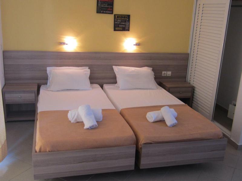 Hotelový pokoj se dvěma jednolůžky, každý s ručníkem a polštářem, měkké nástěnné osvětlení.