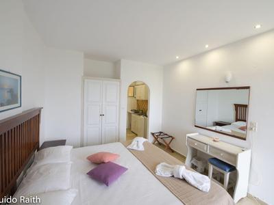 Helles Hotelzimmer mit Doppelbett, Bademänteln, Spiegel und angrenzendem Badezimmer.