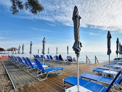 Plage avec chaises longues bleues et parasols fermés sous un ciel bleu.