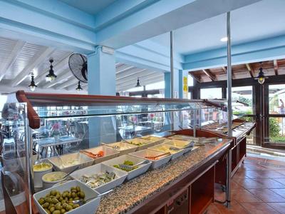 Buffet avec divers plats dans une salle à manger lumineuse et ouverte avec des poutres peintes en bleu.