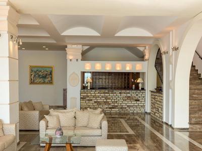 Světlý hotelový lobby s posezením, mramorovou podlahou a recepcí za kamennou zdí.