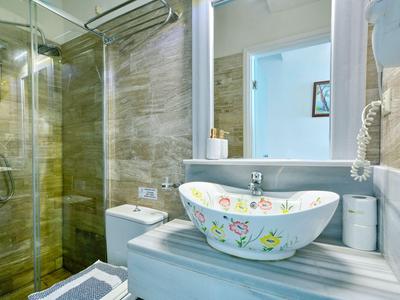 Moderní koupelna s bezbariérovým sprchovým koutem, květinovým umyvadlem a velkým zrcadlem.