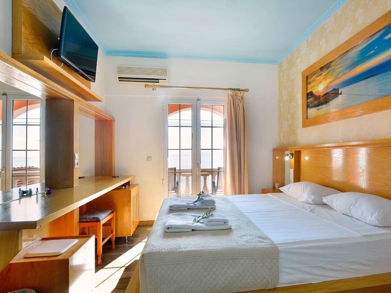 Chambre d'hôtel lumineuse avec lit double, bureau, télévision et balcon avec vue extérieure.