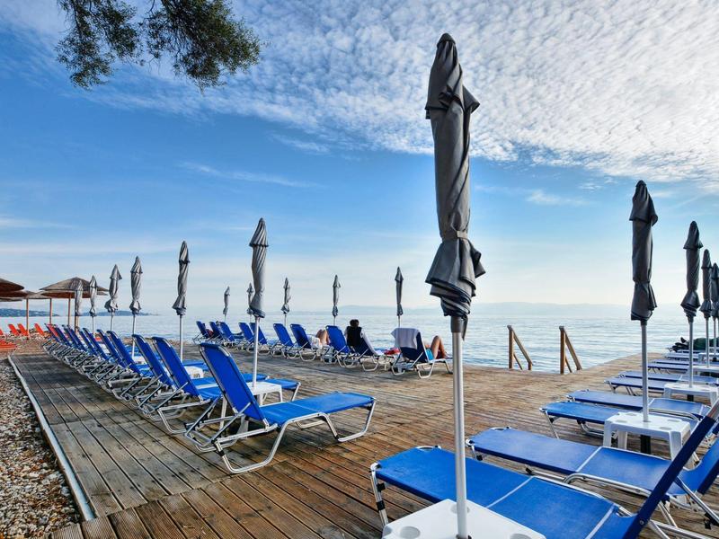 Plage avec chaises longues bleues et parasols fermés sous un ciel bleu.
