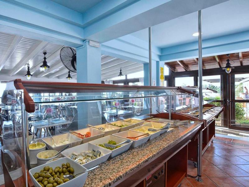 Buffet avec divers plats dans une salle à manger lumineuse et ouverte avec des poutres peintes en bleu.