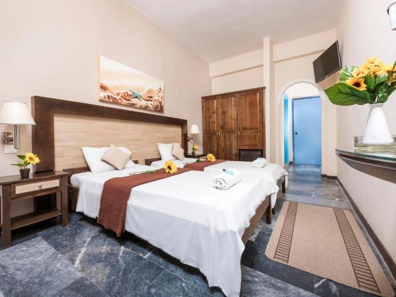 Chambre d'hôtel lumineuse avec deux lits simples, meubles en bois et arrangements floraux.