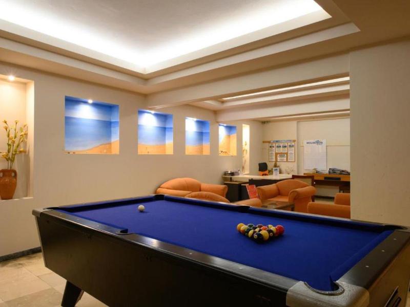 Salle de détente moderne avec billard et sièges confortables sous un éclairage chaleureux.