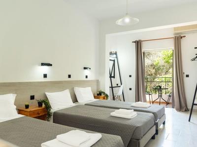 Chambre d'hôtel lumineuse avec deux lits simples, table, balcon et vue sur des plantes vertes