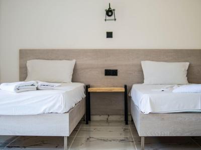 Deux lits simples avec draps blancs et serviettes séparés par une petite table en bois.