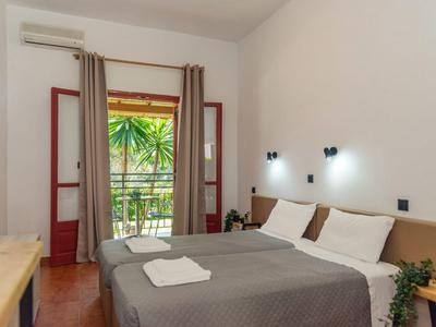 Chambre d'hôtel lumineuse avec lit double, balcon avec plantes et décoration moderne.
