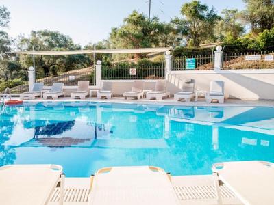 Une piscine extérieure claire avec des chaises longues et des parasols dans un cadre boisé et calme.