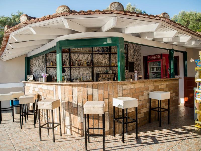 Espace bar en plein air avec tabourets et comptoir sous un toit blanc et cadre vert.