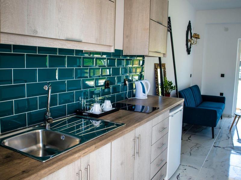 Cuisine moderne avec placards en bois, carreaux verts et vue sur un balcon.