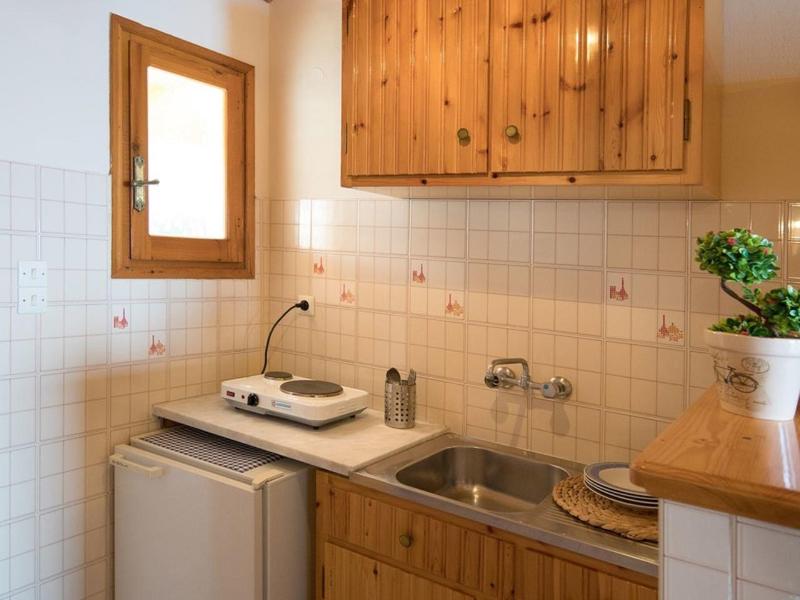 Kompaktowa kuchnia z drewnianymi szafkami, zlewem, mini lodówką i kuchenką w pokoju hotelowym.