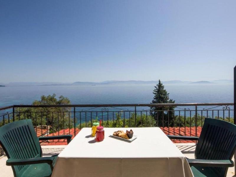 Taras z stołem i krzesłami z widokiem na morze i odległe wyspy pod czystym niebem.